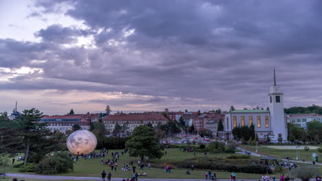 Event-City-Observatory-Brno-Kravi-Hora-Zeitraffer-Von-Sich-Bewegenden-Menschen-Mit-Lunalon-Künstlicher-Mond-Am-Abend-Mit-Dem-übergang-In-Die-Nacht,-Wenn-Der-Mond-Und-Die-Stadt-Aufleuchten