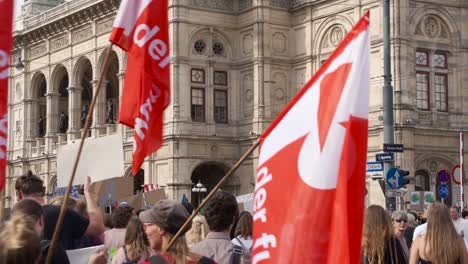Back-view-of-protestors-walking-in-front-of-Opera-facade-during-fridays-for-future-climate-change-protests-in-Vienna,-Austria