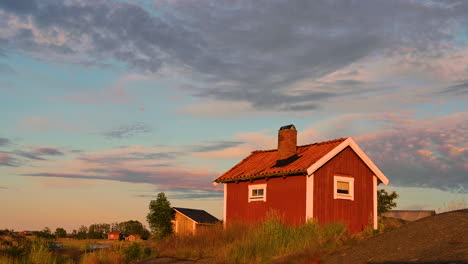 Traditionelles-Rotes-Holzhaus-Auf-Der-Insel-Mit-Brücke-Bei-Sonnenuntergang-Wolken-Himmel-In-Schweden