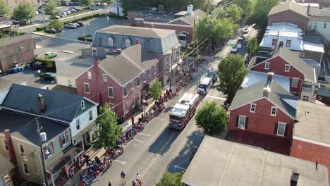 Aerial-zoom-in-on-firetruck-and-Navy-Club-in-Fourth-of-July-Parade,-patriotic-crowds-watch,-wave
