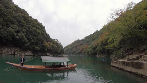 River-boatman-with-guests-on-the-peaceful-Katsura-River,-Arashiyama