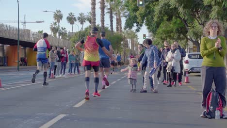 Runners-giving-high-five-at-little-girl-during-Malaga's-marathon,-panning,-Spain