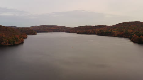 aerial-dolly-out-from-the-reservoir-to-the-waterfalls---orange-tree-tops-at-the-New-Croton-Dam-in-Westchester-County,-NY