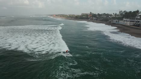 Vista-Aérea-Del-Hombre-Surfeando-A-Bordo-En-Las-Olas-Del-Océano-índico,-Isla-De-Bali,-Indonesia