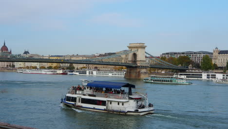 Tourist-ships-sail-in-Danube-River-near-bridge-in-Budapest-Hungary