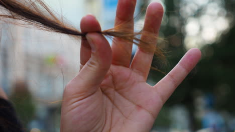 Woman-holds-a-strand-of-hair-in-her-hand