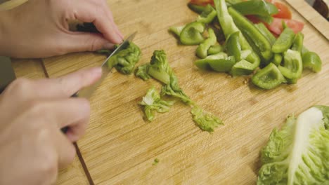 Grüner-Saftiger-Salat-Wird-Auf-Einem-Holzschneidebrett-In-Kleine-Stücke-Geschnitten