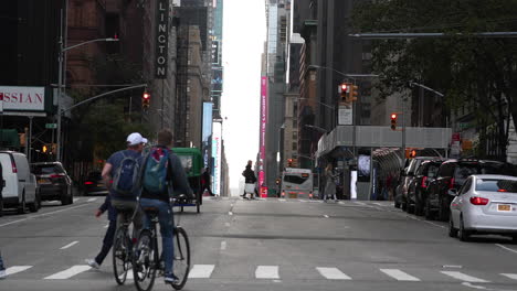 Pedestrian-crossing-and-tourists-biking-on-street-in-midtown-Manhattan,-New-York