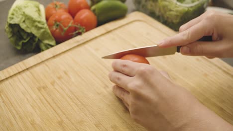 Tomato-is-cut-into-pieces-on-a-wooden-board