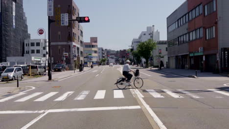 Cámara-Lenta-De-Un-Anciano-Andando-En-Bicicleta-Bajo-El-Calor-Del-Sol-En-Tokio---Toma-Amplia