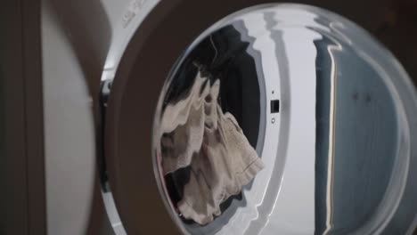 Hand-loading-washing-machine-with-clothes-and-closing-door