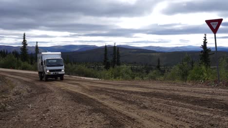 Static-shot-of-a-large-Mitsubishi-Fuso-driving-towards-camera-along-a-dirt-road-in-the-Yukon-region-of-Alaska,-USA