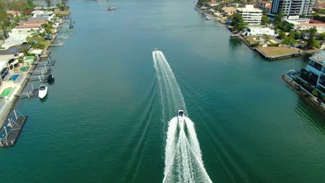 Two-speedboats-racing-along-a-canal-in-the-shadows-of-luxurious-Surfers-Paradise-apartments-and-Luxury-waterfront-houses