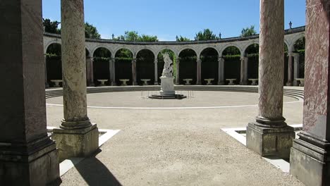 Vista-De-Una-Estatua-De-Mármol-En-El-Centro-De-Una-Pequeña-Arena-En-Los-Jardines-Del-Palacio-De-Versalles,-París,-Francia