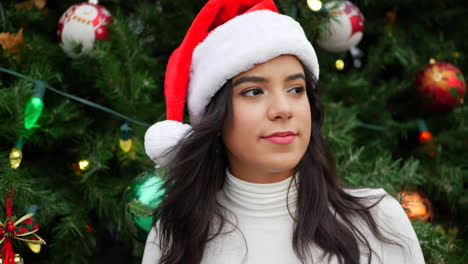 Eine-Schöne-Frau-In-Einem-Weihnachtsmann-Hut-Tanzt-Und-Feiert-Die-Ferienzeit-Mit-Einem-Geschmückten-Weihnachtsbaum-Und-Ornamenten