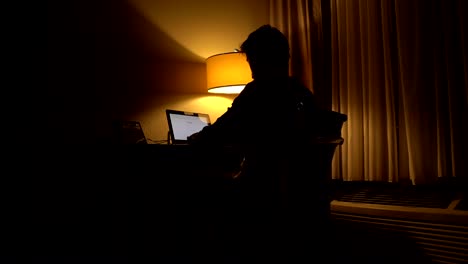 Man-sitting-in-from-of-computer-in-a-dark-room