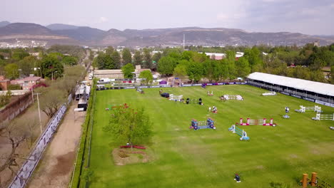 Aerial-rise-over-an-equestrian-show-jumping-course-in-León,-Mexico