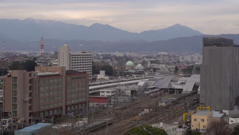 Japón---Tren-Que-Pasa-En-La-Estación-De-Tren-Urbano-Sobre-Los-Ferrocarriles-En-Cámara-Lenta---Toma-Aérea