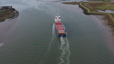 Wide-aerial-reveal-shot-of-the-Peak-Bergen-ship-sailing-along-the-Swale-Estuary-towards-the-Sheppey-Crossing-in-Kent,-UK