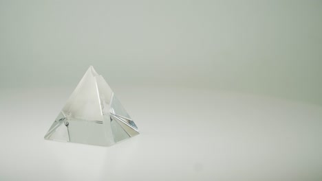Teure-Transparente-Kristallpyramide,-Die-Sich-Im-Uhrzeigersinn-Dreht,-Mit-Reinweißem-Hintergrund---Nahaufnahme