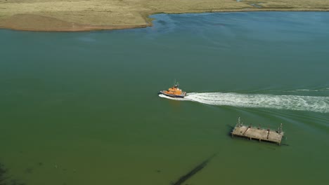 Aerial-shot-of-a-RNLI-Lifeboat-crew-sailing-along-an-open-body-of-water