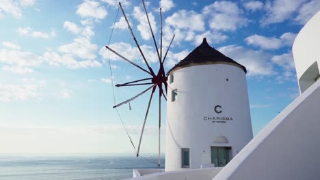 White-windmill-overlooking-the-ocean-with-the-blue-sky-in-the-background,-Santorini,-Greece