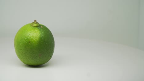 Grüne-Saure-Limettenfrucht,-Die-Sich-Im-Uhrzeigersinn-Auf-Der-Linken-Seite-Des-Drehtellers-Mit-Reinweißem-Hintergrund-Dreht---Nahaufnahme