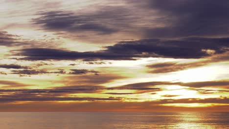 Goldener-Sonnenaufgang-Zeitraffer,-Sonne-Geht-über-Ruhigem-Meer-Durch-Wolken-Auf,-Breite-Aufnahme