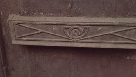 Rusting-vintage-mail-slot-on-wooden-door-with-Spanish-Correos-logo
