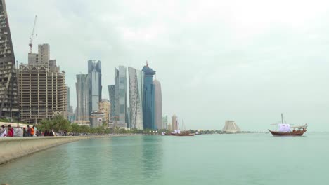 Zeitraffer-Der-Skyline-Von-Doha-Mit-Großen-Flaggen-Und-Traditionellen-Booten-Und-Tamin-Porträt-Auf-Booten