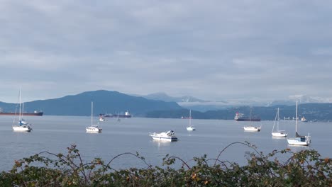 Multiple-boats-and-tankers-anchored-close-to-the-shore-with-snowy-peaks-and-clouds-in-the-background-on-a-sunny-winter-day