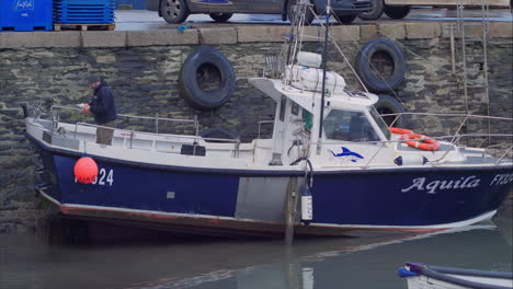 Fisherman-in-Boat-Mevagissey-Harbour,-Cornwall,-England-preparing-for-a-trip,-wide-shot