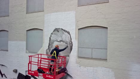 Pintor-De-Graffiti-Creando-Un-Retrato-En-La-Pared-Del-Edificio,-Pedestal-De-Drones