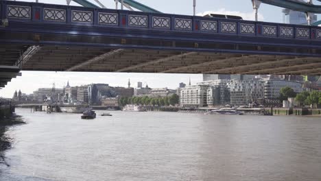 Cinematic-view-under-Tower-Bridge-in-London,-Thames-river-and-boat