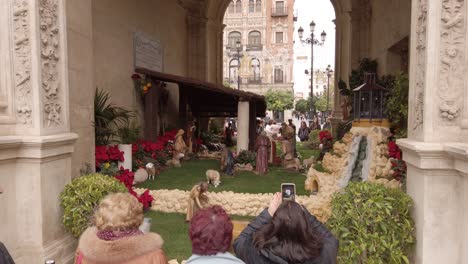 Spanish-people-look-at-Nativity-Scene-outside-church-in-Seville,-Spain,-Slowmo
