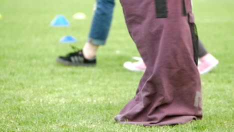 Child-Competing-In-A-Sac-Race,-Jumping-On-A-Grass-Field,-SLOW-MOTION
