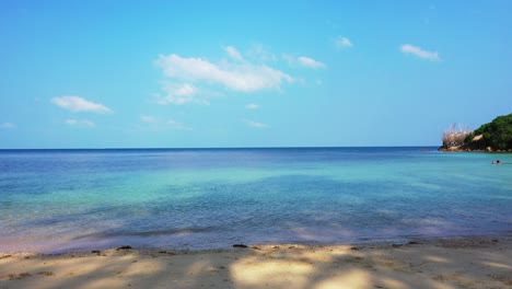 Idyllic-quiet-sandy-beach-washed-by-calm-clear-water-of-shallow-turquoise-lagoon-at-sunrise-bright-sky-in-Jamaica