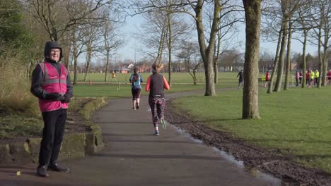 Aktive-Fitnessgruppe-Joggen---Wandern-Im-Nassen,-Regnerischen-Park-In-Zeitlupe-Marshall-Beobachtet-Läufer