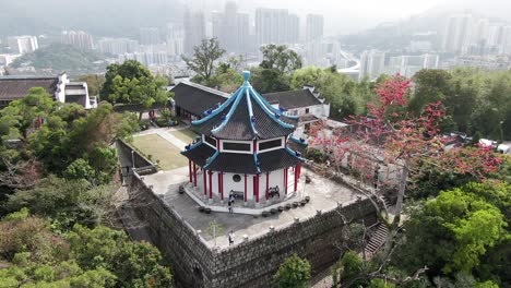 Aerial-view-of-Tao-Fong-Shan-Christian-Centre-Chapel,-Sha-Tin,-Hong-Kong-with-city-skyline-in-the-background