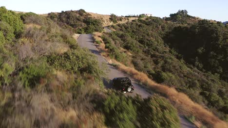 Filmische-Luftaufnahme-Eines-Schwarzen-Jeeps,-Der-Auf-Einer-Asphaltstraße-In-Den-Hügeln-Von-Los-Angeles-Fährt