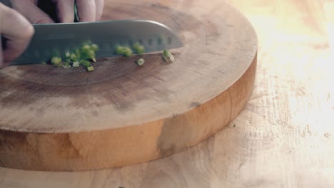 Slow-Motion-Slider-Shot-of-Chefs-Hands-with-Chef-Knife-Chopping-Spring-Onions-on-a-Thick-Wooden-Chopping-Board