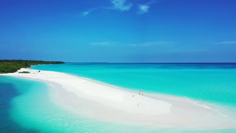 Paradise-tropical-island-with-long-stripe-of-white-sandy-beach-surrounded-by-blue-azure-sea-water-under-a-bright-blue-sky-in-Maldives