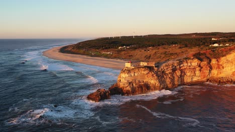 Nazare-Portugal-lighthouse-near-Praia-do-Norte-during-sunset,-Aerial-circle-pan