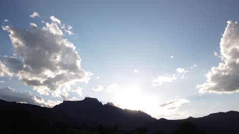 Impresionante-Hiperlapso-De-Tiempo-De-La-Puesta-De-Sol-Detrás-Del-Pico-De-Los-Dragones,-Montañas-Drakensberg,-Sudáfrica,-Destello-De-Lente,-Nubes-Rodantes,-Rayos-De-Sol