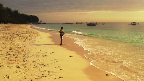 Young-fit-man-fishing-in-the-ocean-waves-of-a-tropical-beach-island-during-the-late-afternoon