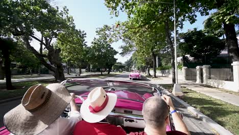 Altes-Cabrio-Rotes-Traditionelles-Klassisches-Auto-Mit-Drei-Freunden-An-Bord,-Die-Durch-Die-Straße-Von-Havanna-Touren