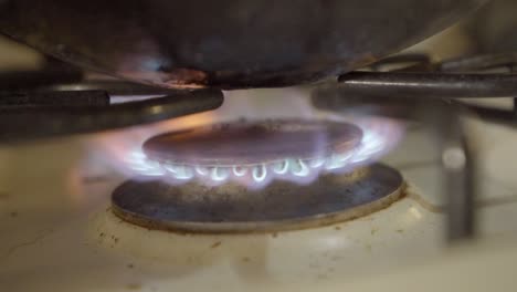 Gas-stove-flame-on-cooking-hob-heating-up-wok,-closeup-of-flame