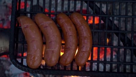 Delicious-sausages-on-an-open-flame-grill-barbecue-campfire,-with-copy-space