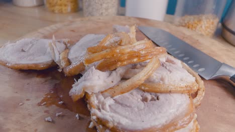 Slider-Shot-of-Sliced-Belly-Pork-Joint-with-Crispy-Crackling-on-a-Wooden-Cutting-Board-in-the-Kitchen