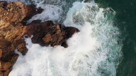 Ocean-rock-battered-by-waves-in-Praia-Do-Tonel,-near-Cape-Sagres-Portugal,-Aerial-rising-circle-shot